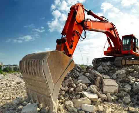 Orange excavator working on a concrete demolition site
